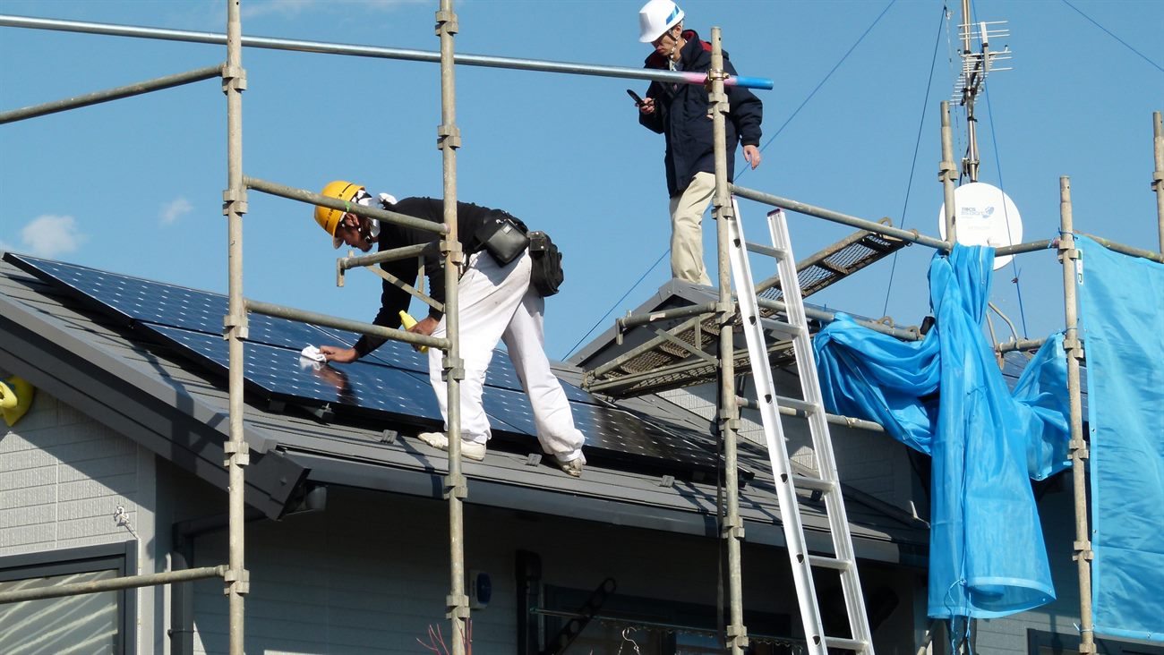 Technicians installing solar panels on a roof